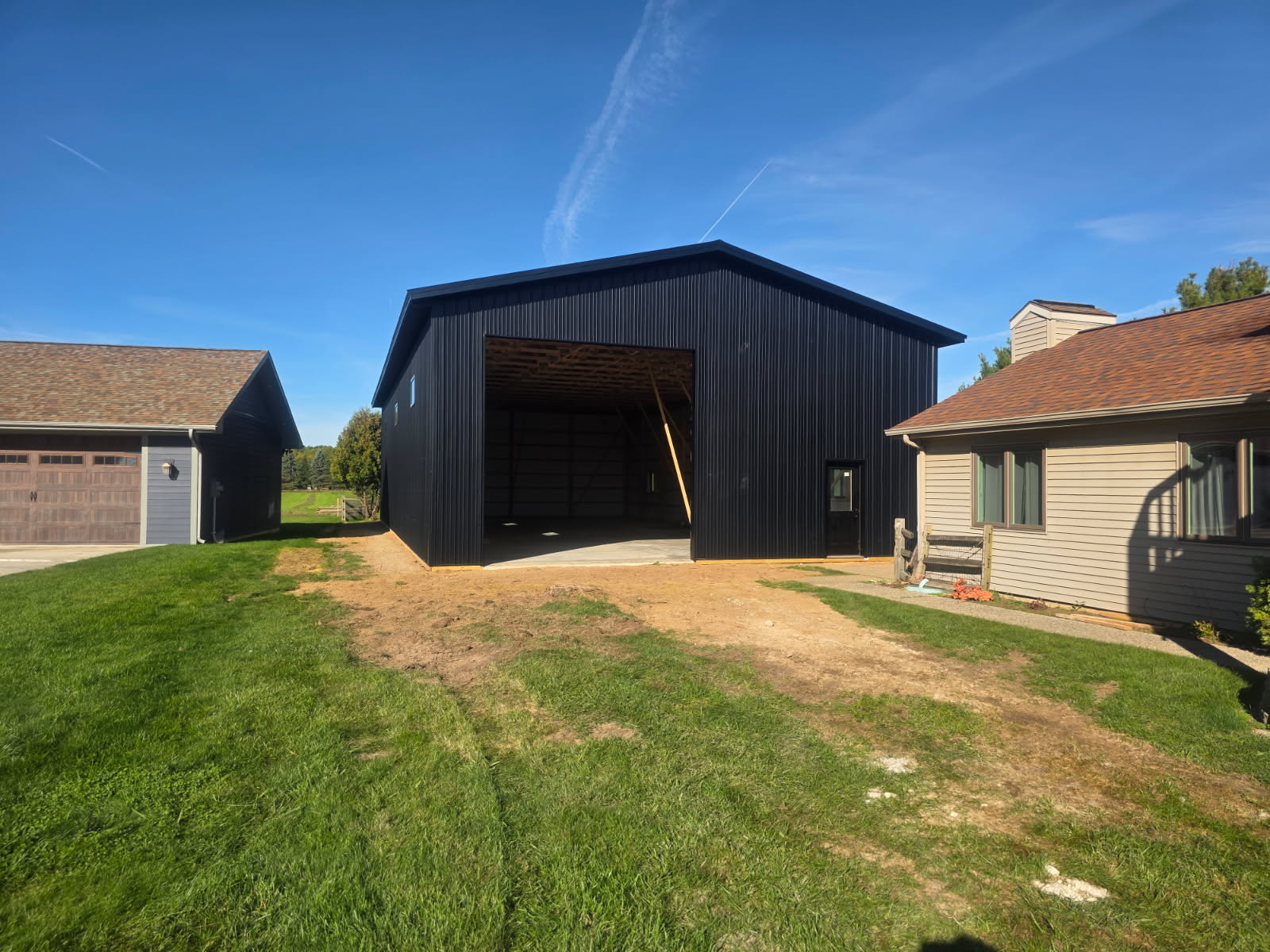 New black metal pole barn with concrete slab floor and tall overhead door opening built in Northern Indiana