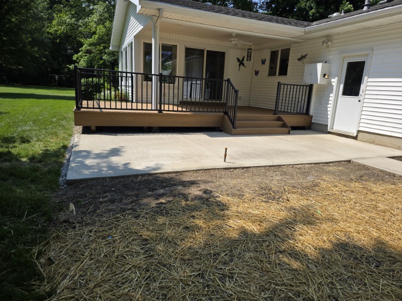 Low profile composite deck with black aluminum railing and adjoining concrete patio in Northern Indiana