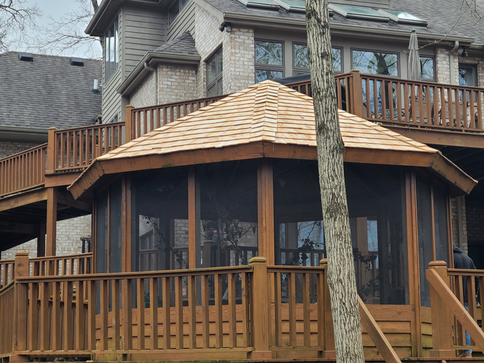 Custom screened cedar gazebo with shake roof built beside a lake home