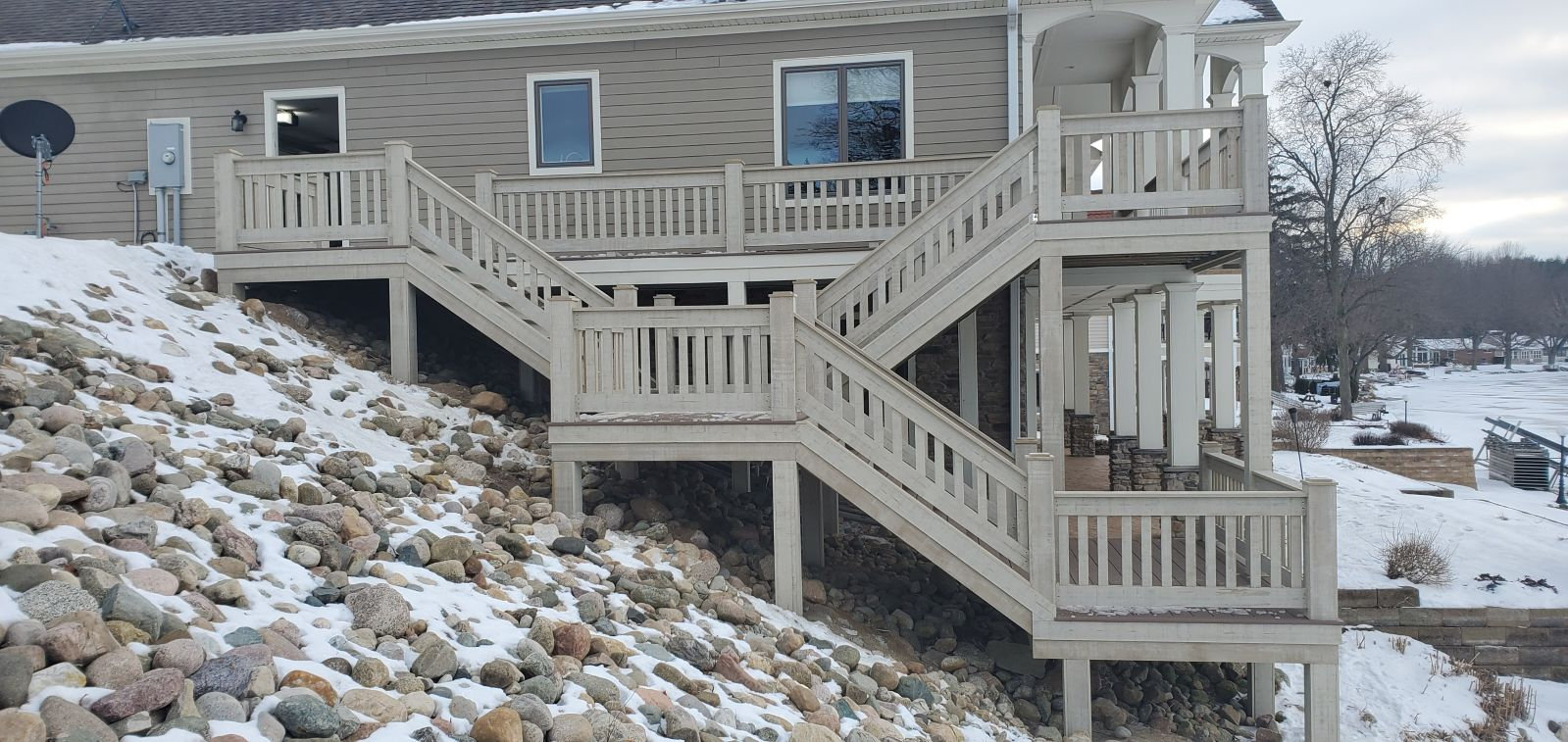 Multi level wood deck with stairs built on a hillside lake home