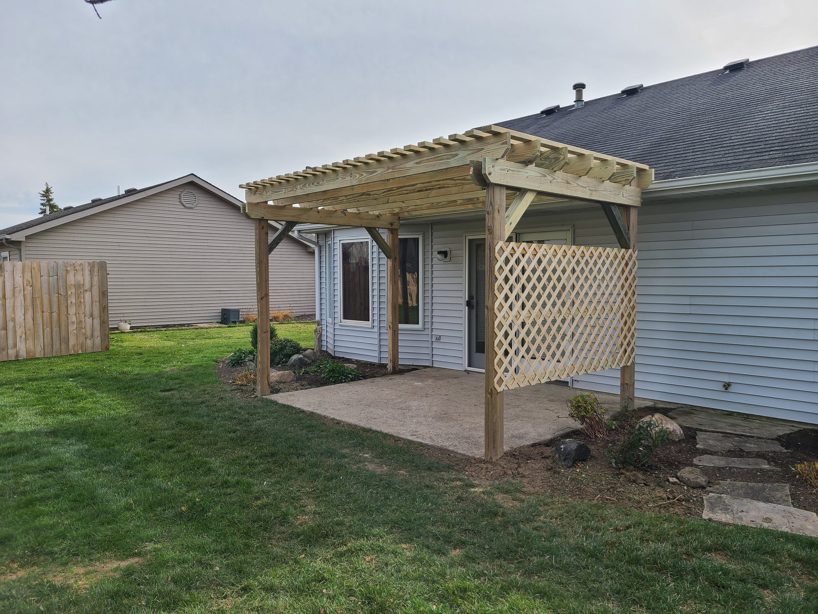 Wood pergola shading a backyard concrete patio