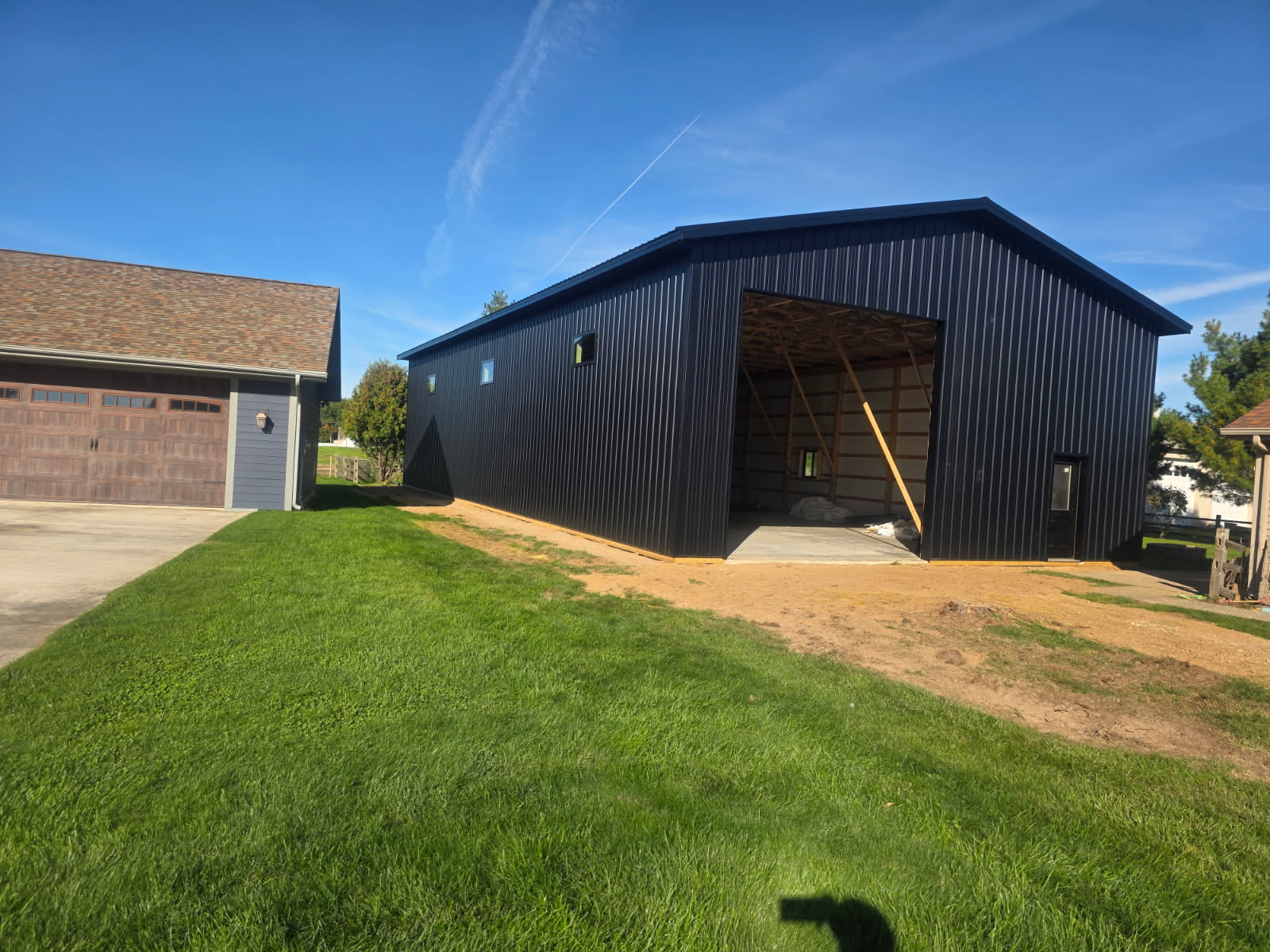 Black metal pole barn garage with high sidewalls, high clerestory windows, and an open vehicle bay