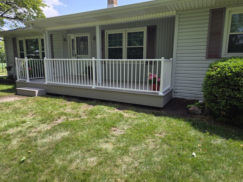 Covered front porch with white vinyl railing and composite decking on a Northern Indiana home
