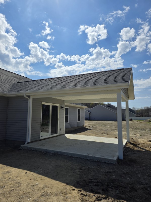 New covered concrete patio addition with painted white posts and matching soffit