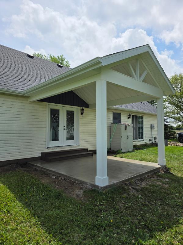 Covered back porch addition with white gable roof and stamped concrete pad on a Northern Indiana home
