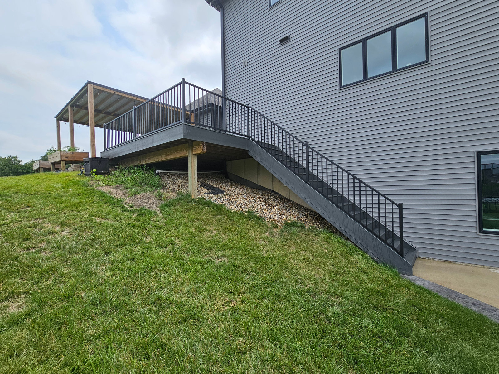 Elevated covered deck with long stairway and black railing on a Northern Indiana home