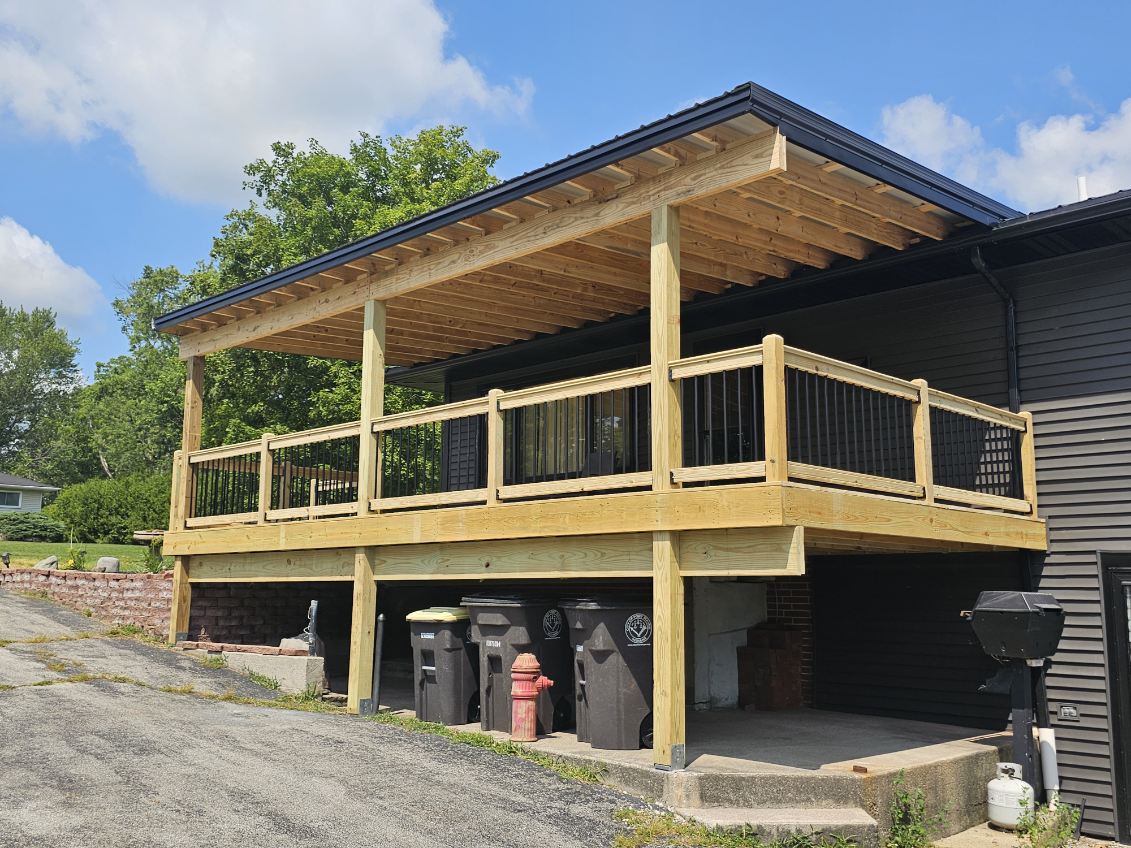 Elevated covered pressure treated deck with black metal balusters and shed roof