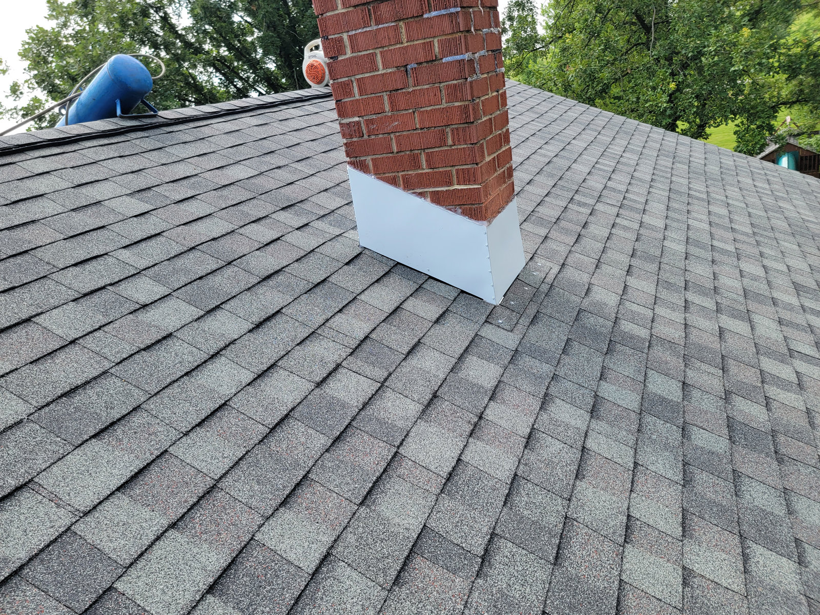 New architectural shingle roof with chimney flashing installed by T&J Construction