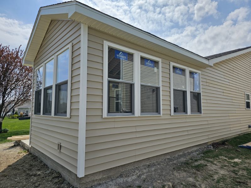 Side view of a sunroom room addition with tall windows and matching vinyl siding