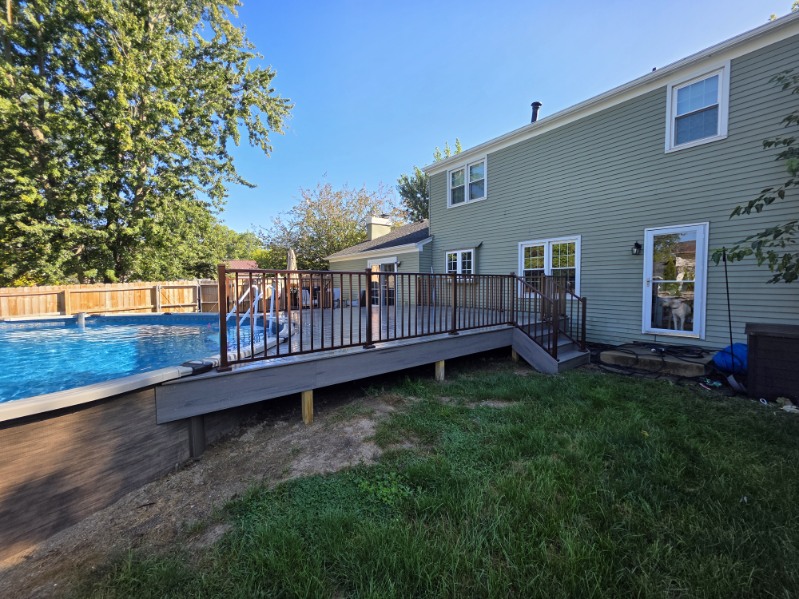 Side view of a composite deck with bronze aluminum railing built along an above ground pool